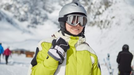 ヘルメットとゴーグルを着けてスキーウェアを着た女性