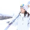 スキー板を担いでゲレンデを歩く女性