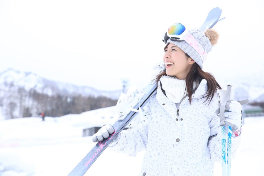 スキー板を担いでゲレンデを歩く女性